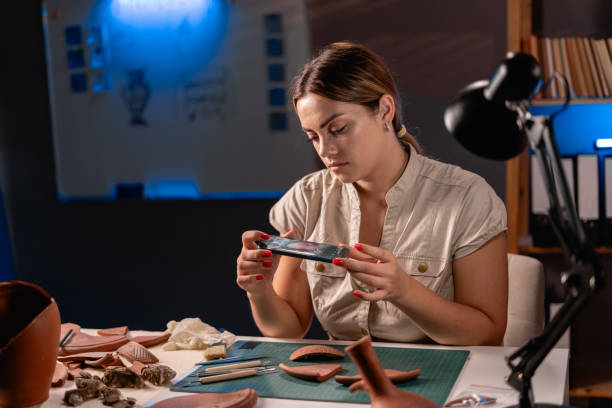 istock An archaeologist working at night in the office photographs an archaeological artifact using a smartphone. 2015764219