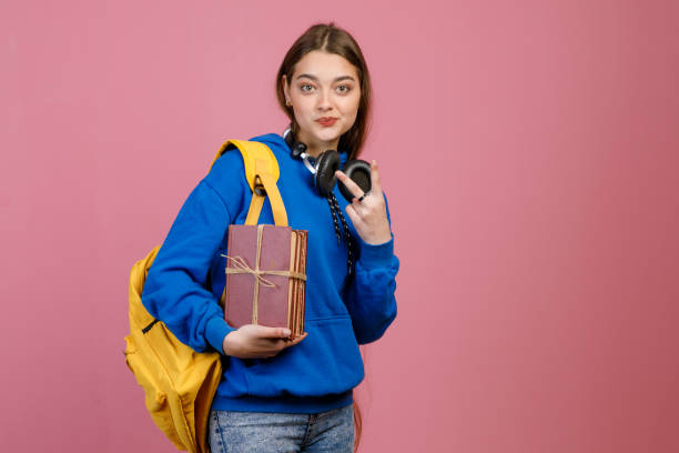 istock Pretty schoolgirl standing, smiling, showing peace, greeting. 2015766263
