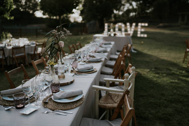 istock Table for wedding celebration. Elongated table located in the meadow on green grass, at the end of the table there is a illuminated sign that says love. 2015770470