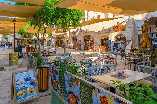 A colorful sidewalk cafe inside the Dubai Creek historical district, with authentic Arabic looking buildings housing shops and restaurants at the Bur Dubai Souk Market shopping and culture center along Dubai Creek, in Dubai, United Arab Emirates. Dubai Creek has been described as a natural saltwater creek, tidal inlet, and watercourse or waterway in Dubai, United Arab Emirates. It extends about 9 miles inwards and forms a natural port that has traditionally been used for trade and transport.