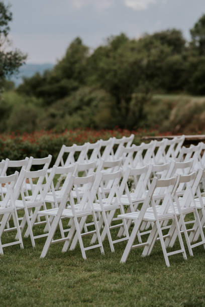 istock Many white folding chairs placed in order in a natural environment. Natural environment, esplanade with grass and mountains in the background. 2015799488