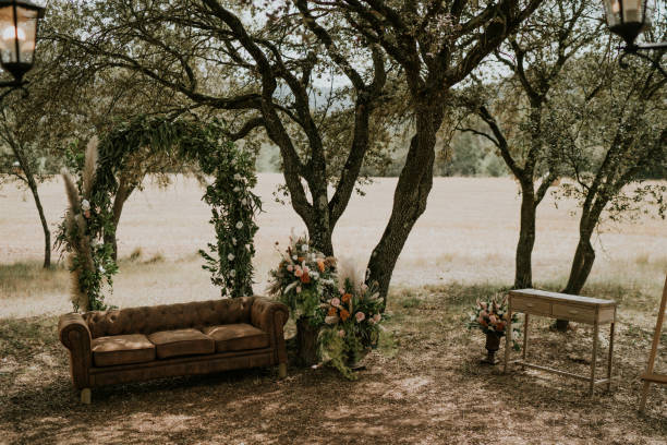 istock General shot of an altar for a rustic ceremony held in a natural setting. We see a sofa with an arch made of flowers and plants. Next to the leather sofa, a large bouquet of pink roses and pampas feathers. 2015799509