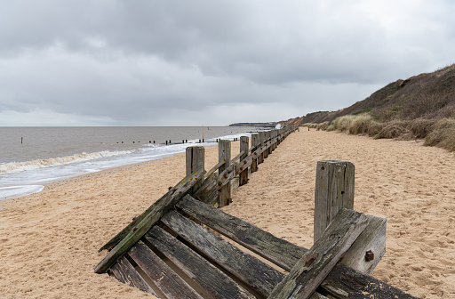 wooden sea defense groynes buried in the sand on the beach