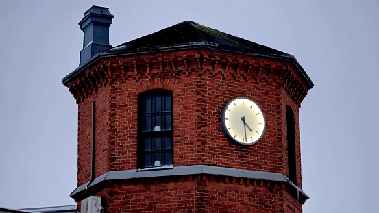 A picturesque image of a magnificent brick-built clock tower amidst a cloudy winter sky.