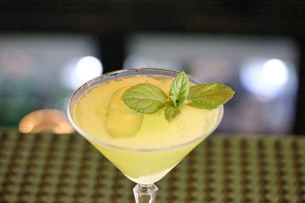 A glass filled with a refreshing yellow drink topped with a vibrant green leaf.
