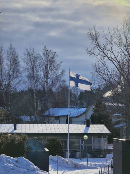 Finnish flag during the winter season with snow and beautiful background trees in partly cloudy weather.