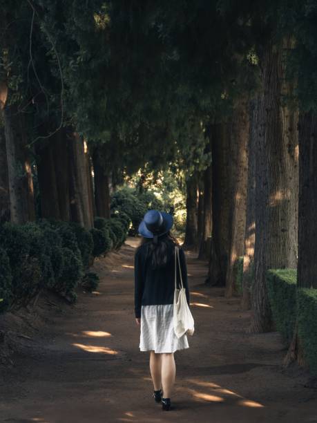 istock Woman walking along treelined path 2015886977