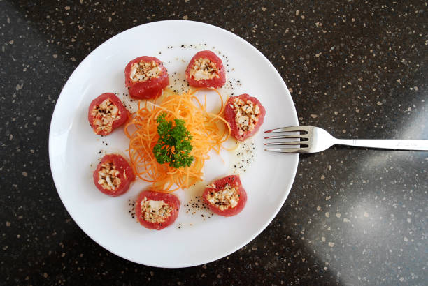 tuna rolls stuffed with grated carrot served on plate on stone background in restaurant, top view