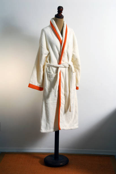 istock White bathrobe or bathrobe with bright oranges hanging on its rack on a white background, wall in loft style 2015904634