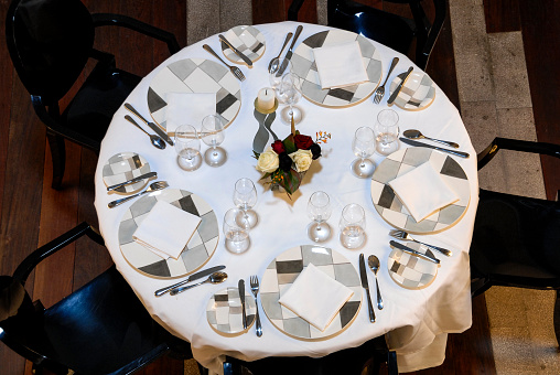 Luxury restaurant table top view, decorated plates, cutlery, glasses and napkins on the table, decorated with vase and candle, modern style restaurant interior