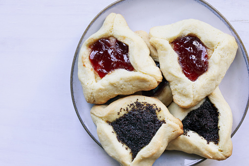 Variety of traditional hamantaschen cookies filled with mohn paste (poppy seed paste) and plum jam for the Jewish festival of Purim. Table top view.