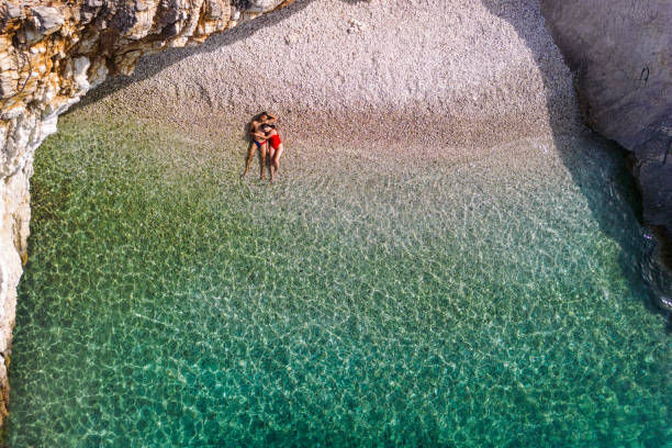 Couple enjoying vacation and relaxing alone on the beautiful beach.  Young woman and man in love sunbathing and color of water is amazing. Filiatro beach, Ithaca Island, Greece