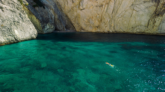 Beautiful and graceful young woman snorkeling in small cove on remote island with perfect clear water. Meganisi island, Greece