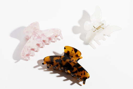 Amber, white and pink plastic hair Claws clips on white background. Hair accessories.