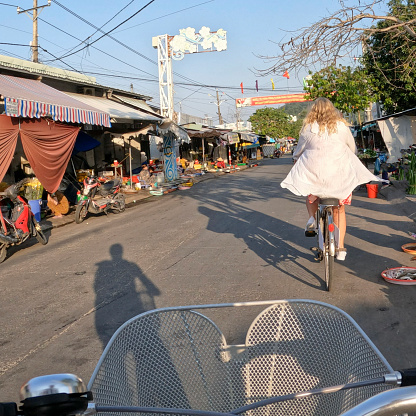 Personal perspective of couple riding bicycles through village