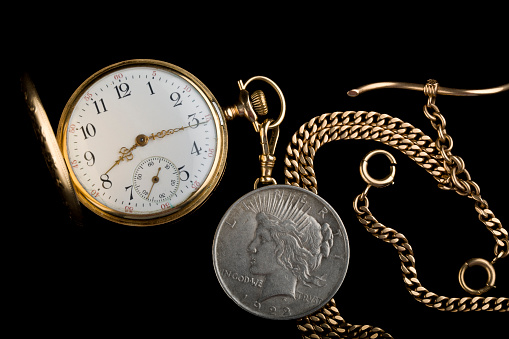 Antique golden pocket watch showing a few minutes to midnight isolated.