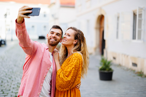 Photo of young couple taking selfie while having fun outdoors