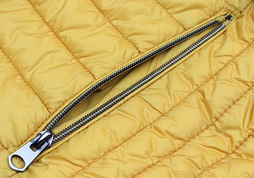 Unzipped metal zipper on the pocket yellow jacket close-up