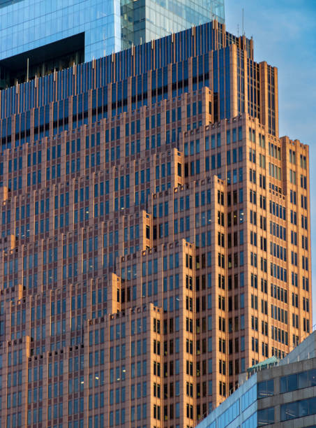 Although this skyscraper is named Three Logan Square, it actually is located several blocks away at 1717 Arch Street. \n\nThe north facade seen here consists of successively shorter and narrower slabs, giving the impression of set-backs or a ziggurat feel to the building. Here, the late afternoon light sets it off from its surroundings, including the taller Comcast Building in the background.