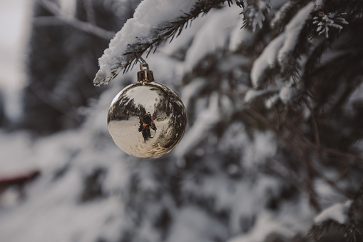 Two of four candles are burning for the second Advent on fir branches with Christmas decoration against a grey background, copy space, selected focus, narrow depth of field