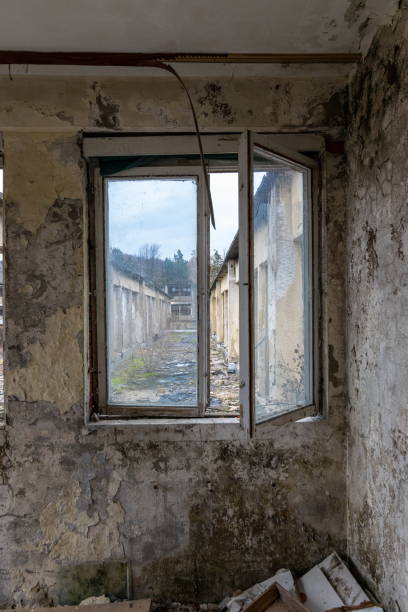A look through a window of an old looted factory falling apart crumbling bricks gravel concrete stock photo