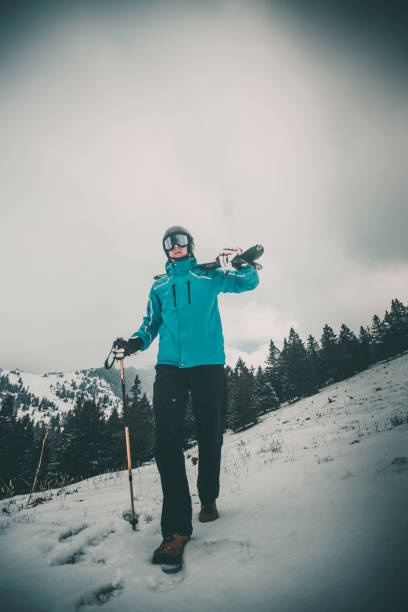 Skier pauses in snowy forest with moody light