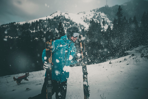 Skier pauses in snowy forest with moody light