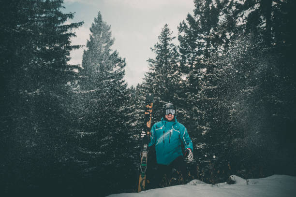 Skier pauses in snowy forest with moody light