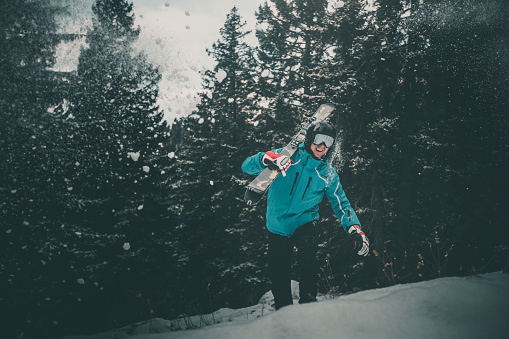 Skier pauses in snowy forest with moody light