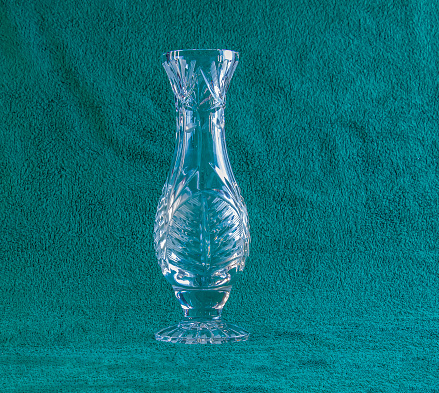 Empty crystal vase on green background. The vase was made in the mid-20th century.