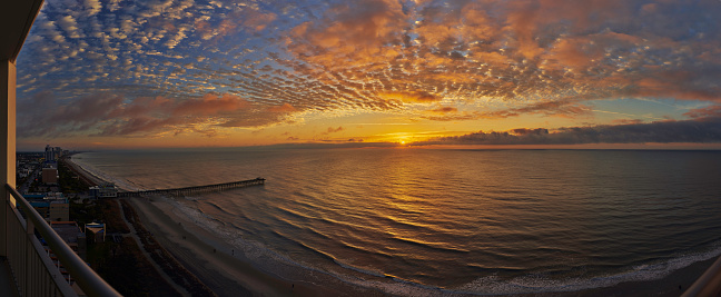 a panoramic view of a myrtle beach sunrise, and the atlantic ocean, from a hotel balcony above this touristy beach, in south carolina.