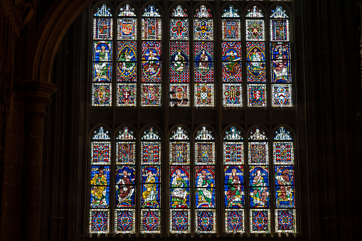 Vivid colours shine from gothic stained glass windows in Canterbury Cathedral. Colourful and beautifully detailed portraits of historical figures in religious and pilgrimage building in United Kingdom