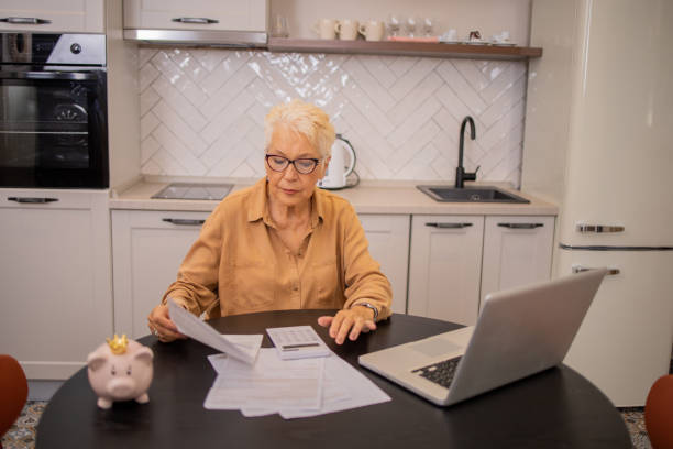 istock Senior woman using calculator while going through bills and home finances 2016369058