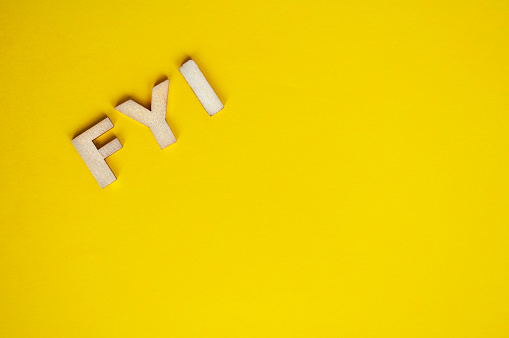 Top view of wooden FYI text on yellow background with customizable space for text.