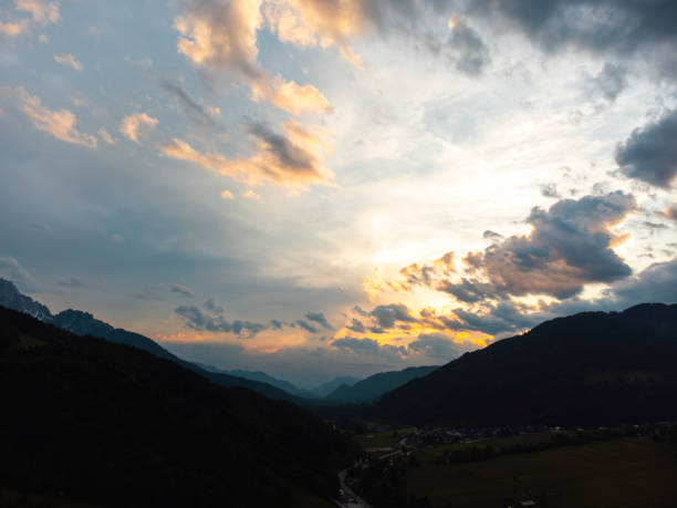 Cloudy sky with setting sun above a green mountainous valley