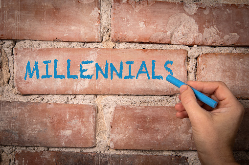 Millennials. Text written with purple chalk on a red brick background