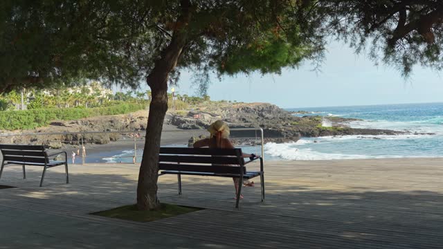 Young attractive woman walk and sits under the tree near Atlantic ocean