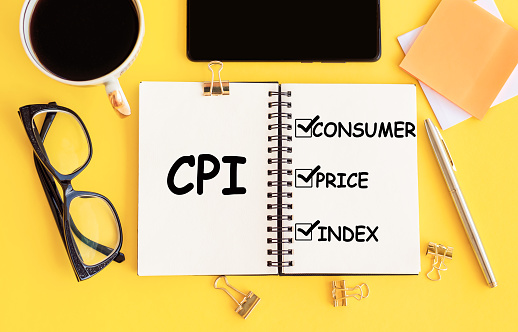 CPI - Consumer Price Index acronym, with text on notepad and office accessories on yellow desk.