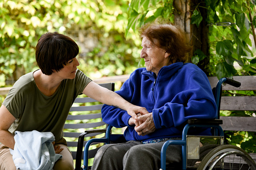 Senior woman in a wheelchair and a caregiver in a park