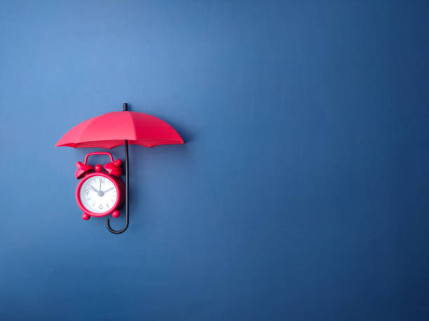 istock Red umbrella and red alarm clock on a blue background 2016578777