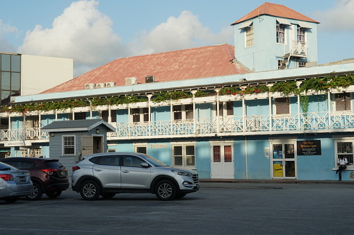 Bridgetown, Barbados 02 02 2024: Blue house in typical bright colors and colonial style decorated by red flowers on the Caribbean island of Barbados in Bridgetown situated near main road and seaport.