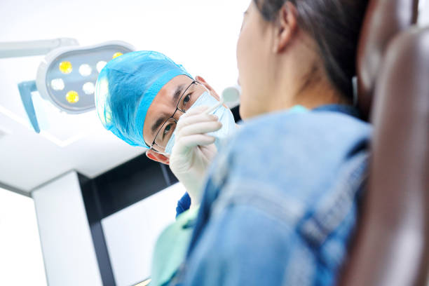 Asian dentist examining teeth to young female patient in dental's clinic.