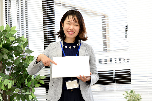 Young asian woman holding blank message card indoors