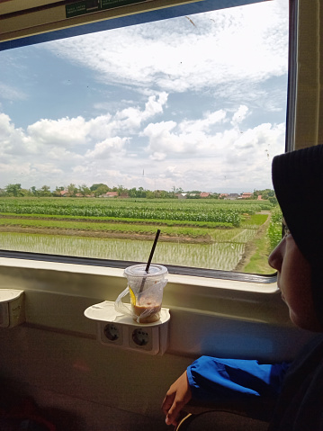 Indonesian hijab female train passenger is enjoying the view.