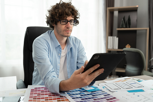 Caucasian businessman use tablet computer working with color chart at office