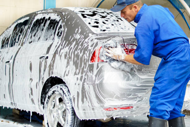 istock a man in blue overalls washing a car 2016888210