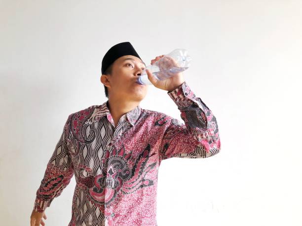 istock Asian muslim man drinking from plastic water bottle on isolated background 2016914410