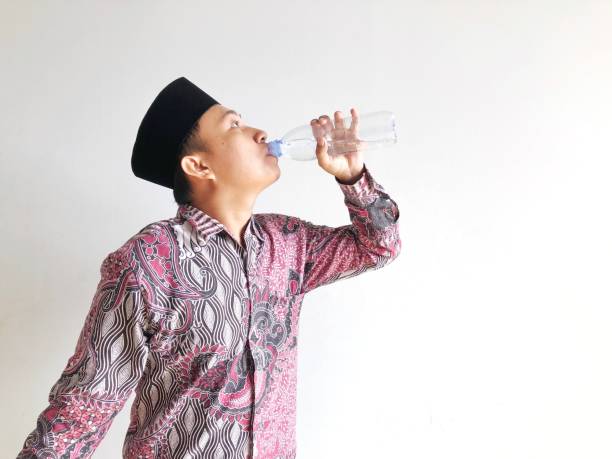 istock Asian muslim man drinking from plastic water bottle on isolated background 2016914420