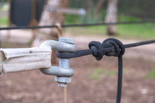 black rope attached to metal tensioning and connecting equipment. Holder Sling rope.