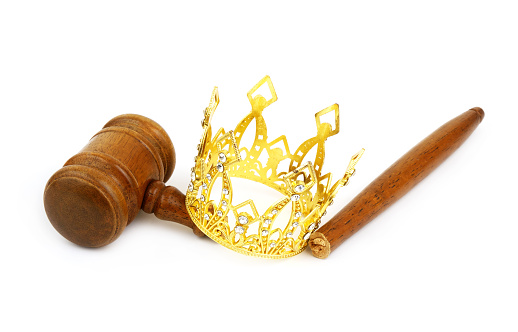 Monarchy, injustice and court concept. Gold crown with broken judge gavel isolated on white.